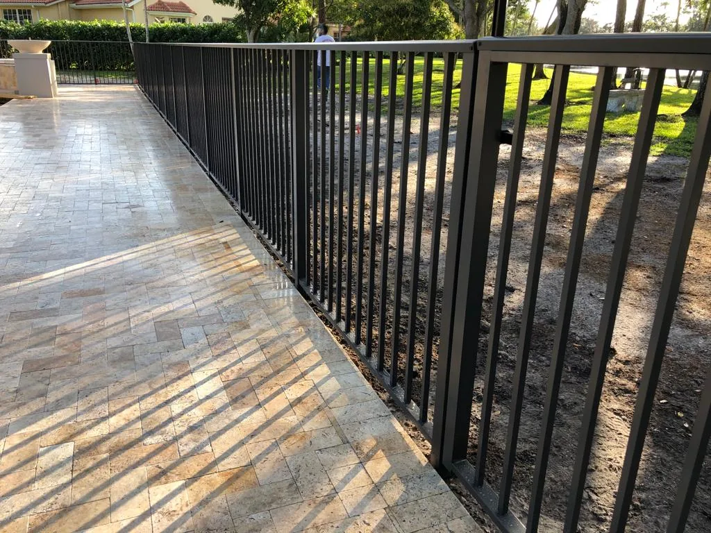 Black aluminum picket fence beside a stone paver patio