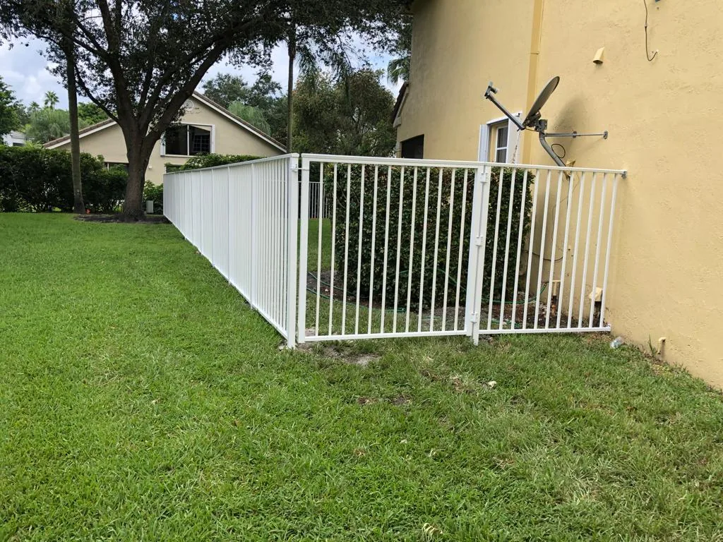 White aluminum picket fence with a gate along a grassy side yard