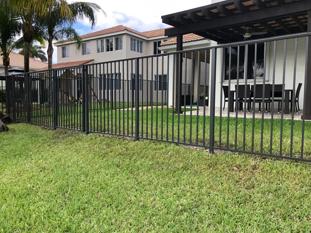 Black open-picket fence surrounding the lawn outside a house