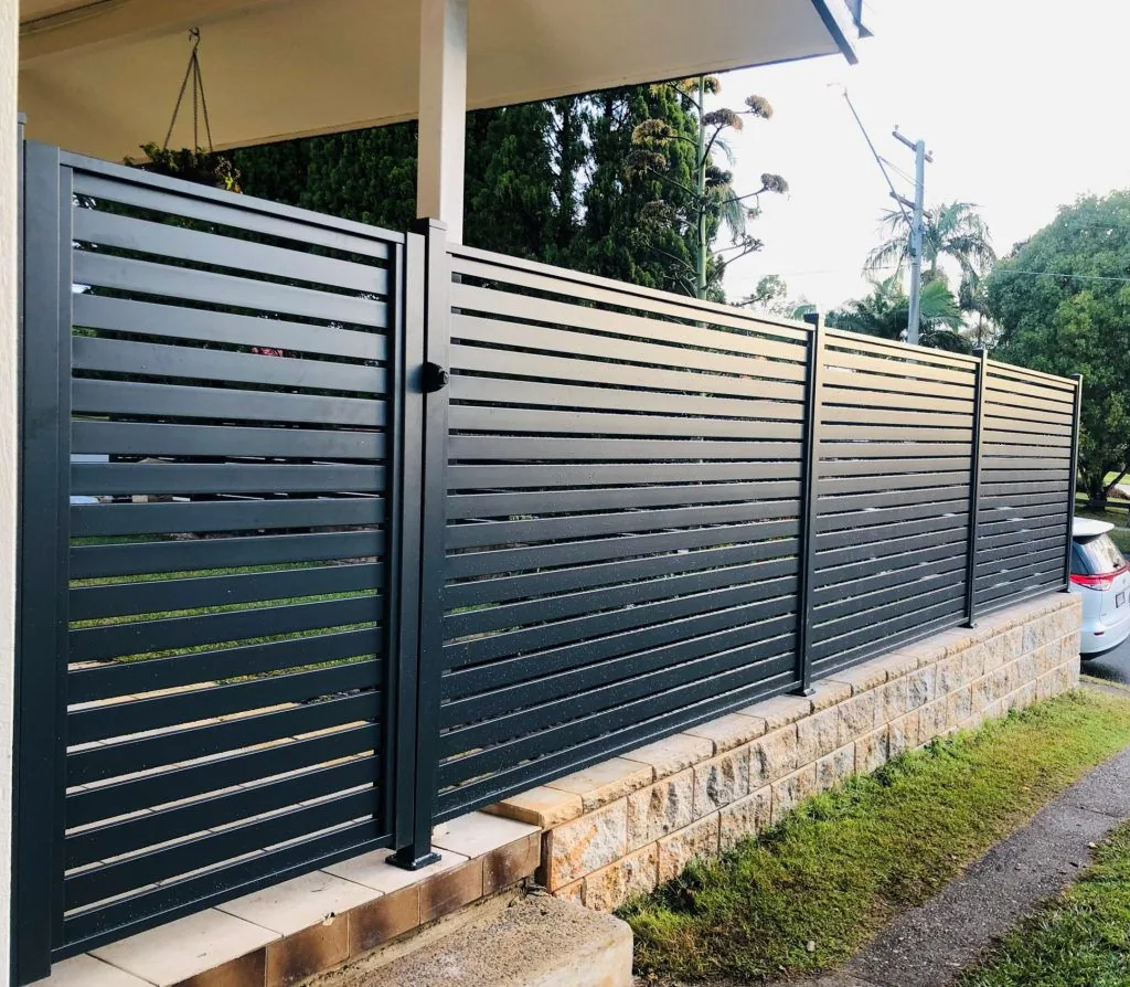 Dark horizontal-slat fence panels and a gate beside a covered patio