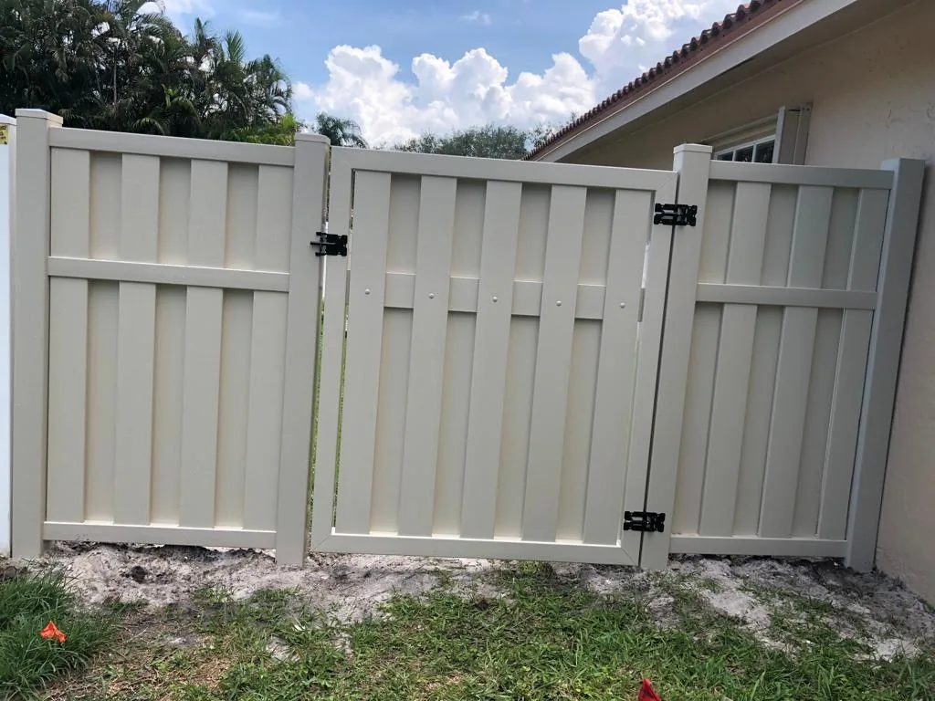 Beige shadowbox-style vinyl double gate in a fence line