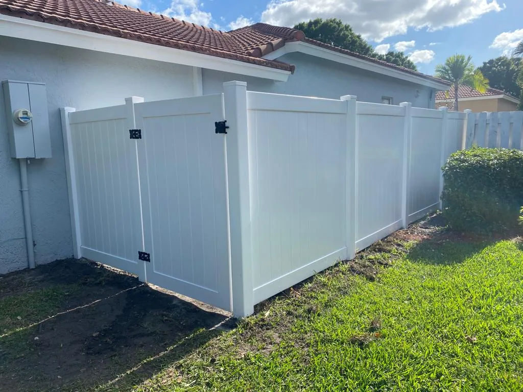 White vinyl double gate beside a house