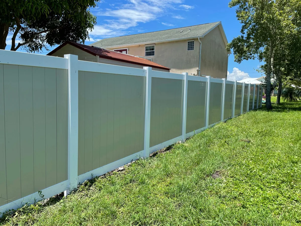 Two-tone vinyl privacy fence along a South Florida backyard lawn