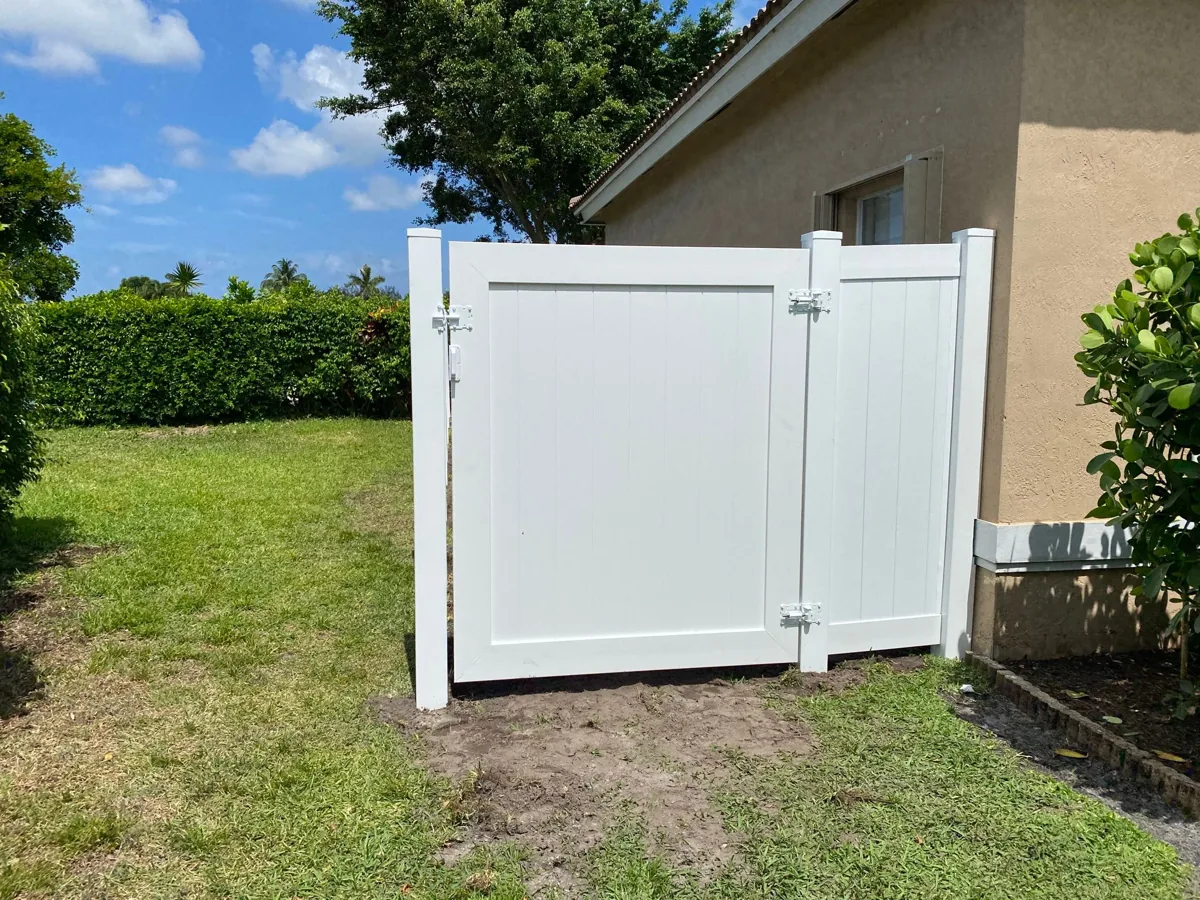 White vinyl gate adjacent to a home and planted lawn