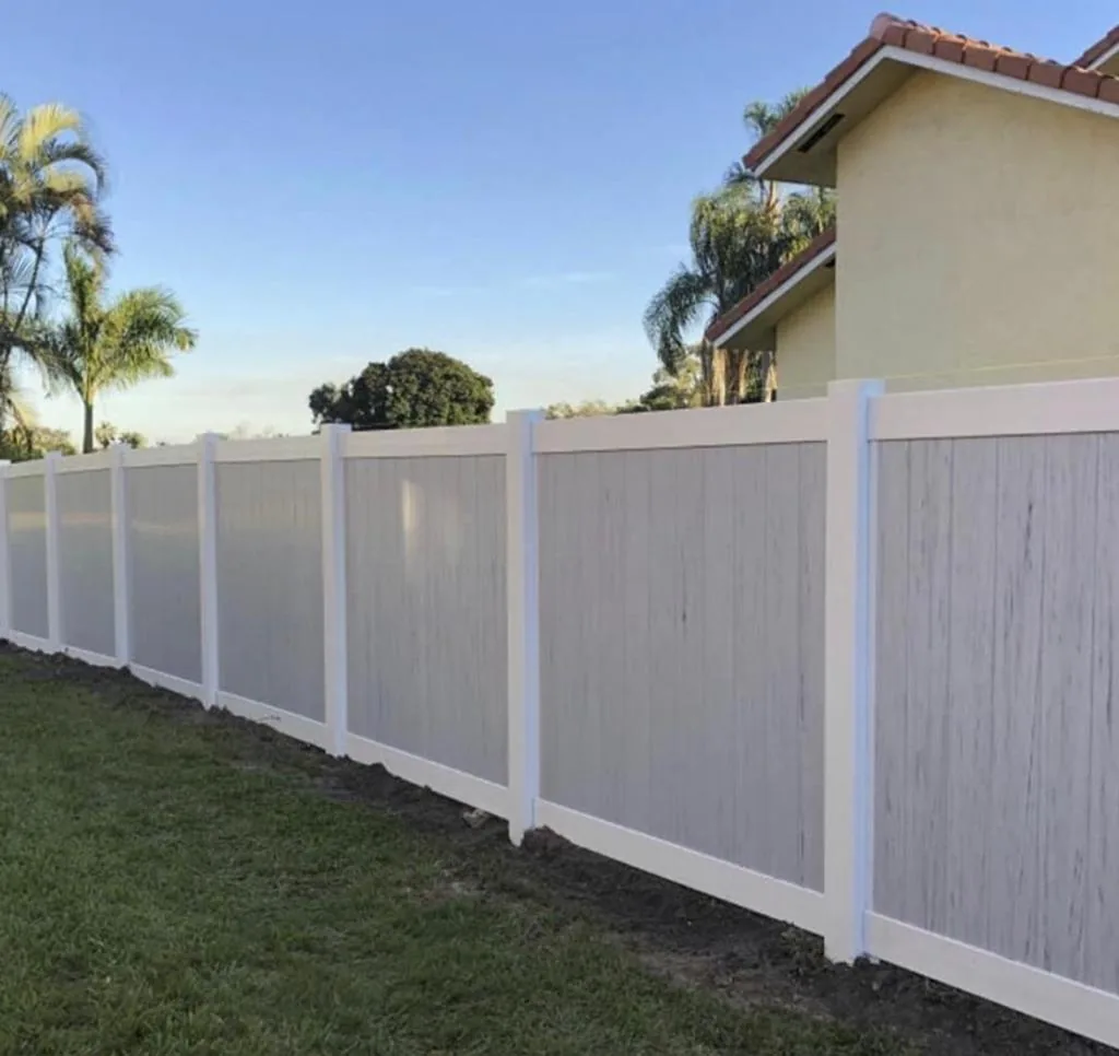 Light gray vinyl privacy fence with white posts along a yard