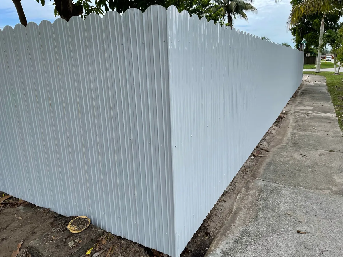 White vinyl privacy fence with a scalloped top along a sidewalk