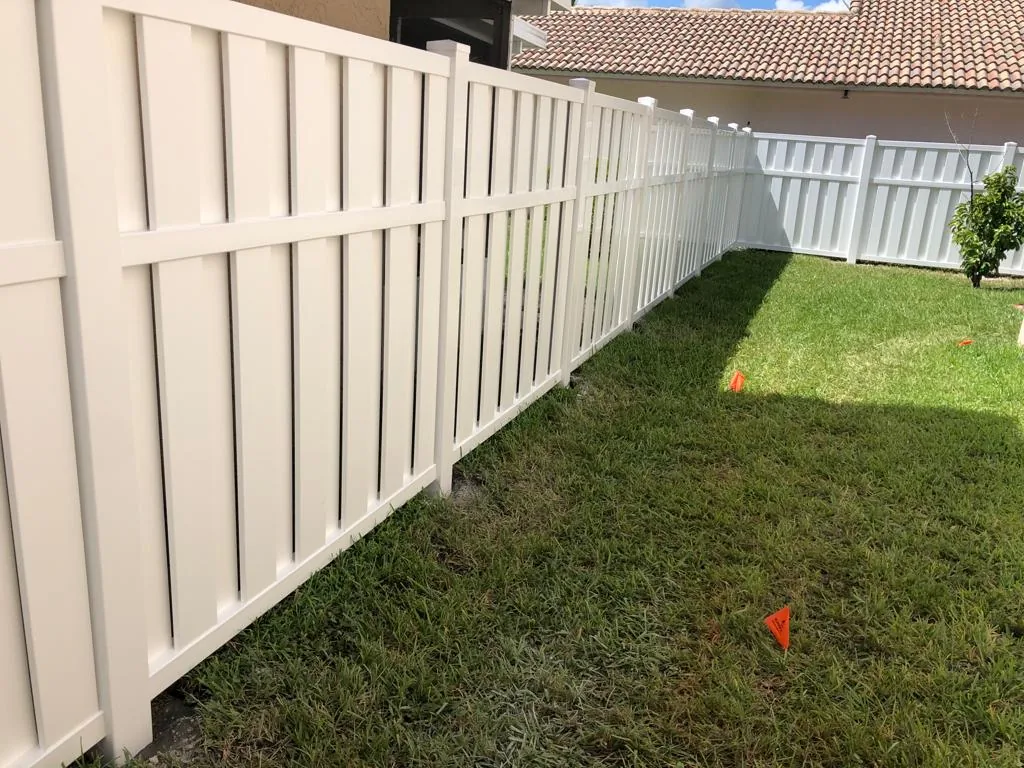 Beige shadowbox-style vinyl fence along a backyard