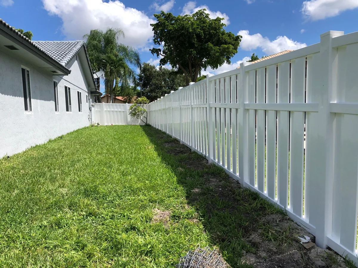White shadowbox-style vinyl fence beside a house and lawn
