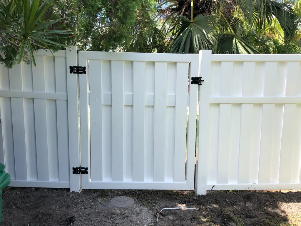 White vinyl shadowbox gate with black hinges between fence panels