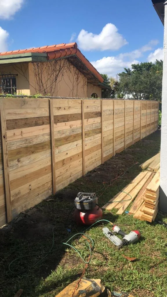 Horizontal wood fence under construction with tools on the grass
