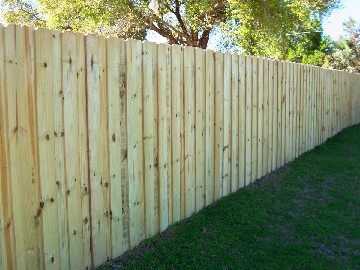 New vertical wood board fence running along a grassy yard