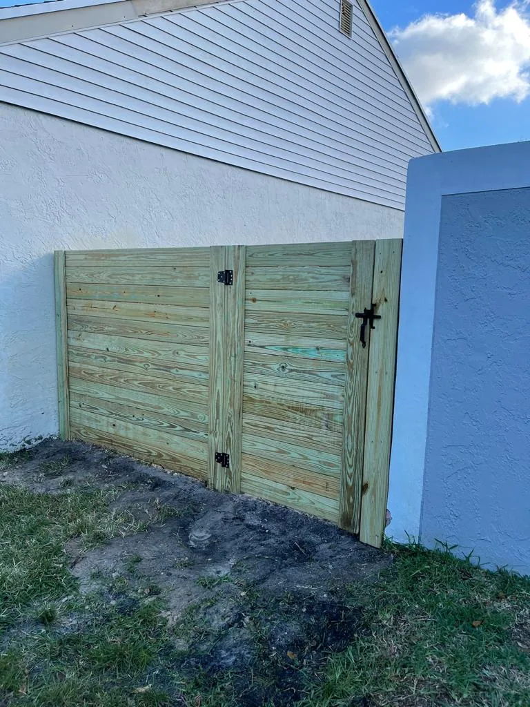 Horizontal wood gate with black hardware beside a house wall