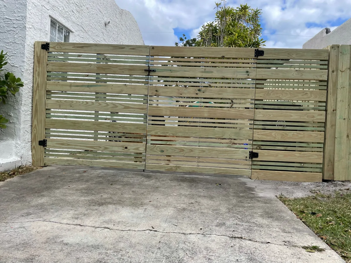 Wide wood driveway gate with horizontal slats and black hardware