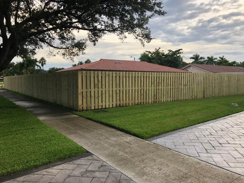 Wood privacy fence enclosing a lawn beside a sidewalk